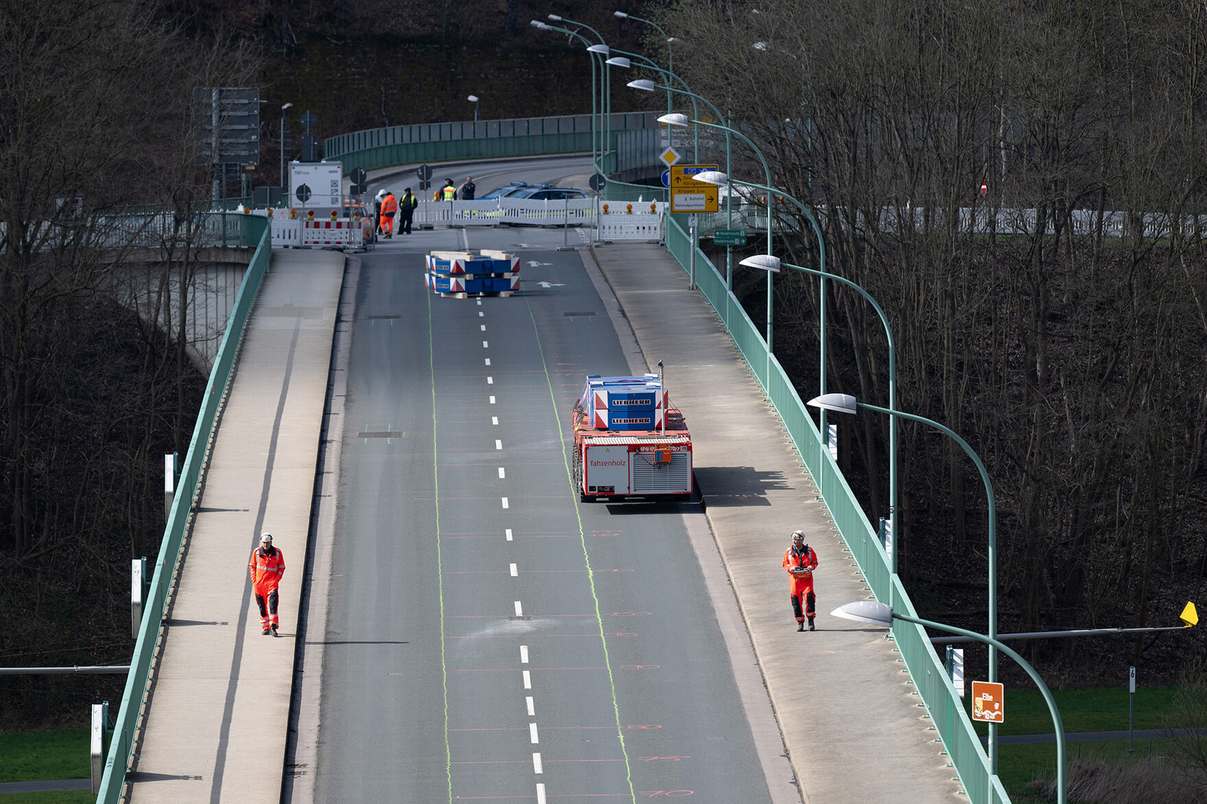 Zwei Männer und ein Schwerlastauto stehen auf einer Brücke.